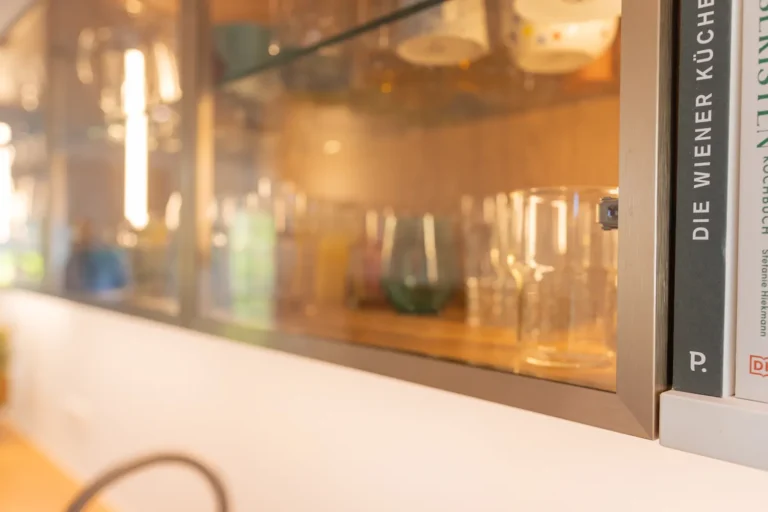 Hochwertige Oberschränke mit Glasfronten und LED-Beleuchtung – stilvolle Präsentation von Gläsern in einer individuell geplanten Designküche.