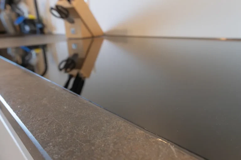 Edle Arbeitsfläche mit eingelassenem Kochfeld in dunkler Steinoptik – reflektiert Design und Klarheit der Umgebung.