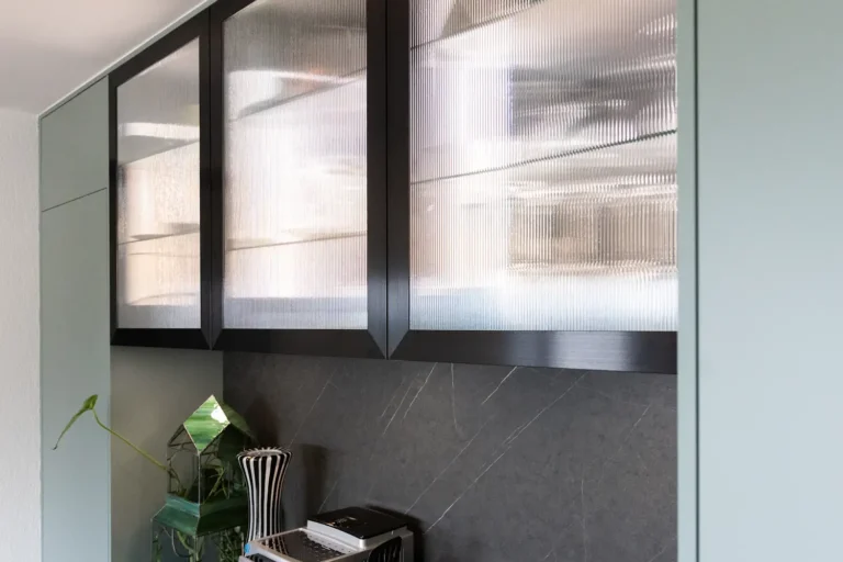 Hochwertige Oberschränke mit schwarzem Rahmen und satiniertem Riffelglas vor dunkler Steinwand