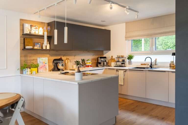 Moderne Familienküche in Karlsruhe Grötzingen mit Halbinsel, Kaschmirfronten, graphitfarbenen Hängeschränken und Arbeitsplatte in Carrara Marmoroptik.