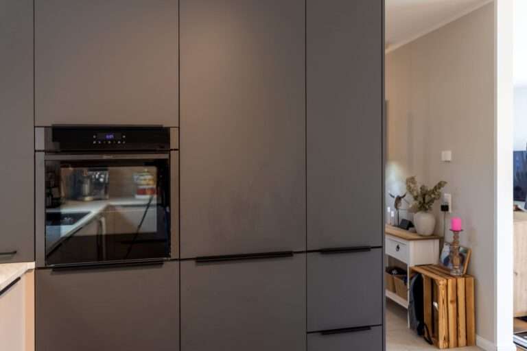 Hochschrankwand in Graphit mit integriertem Backofen, Kühlschrank und Vorratsschrank in einer modernen Familienküche.